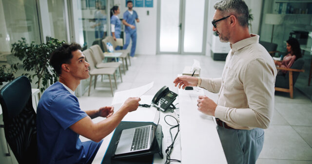 Patient receiving their treatment plan at the front desk at a medical office.
