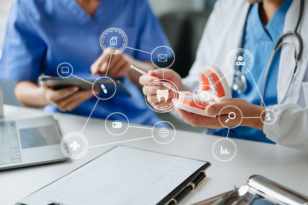 Two healthcare professionals review digital information while holding a dental model, with connected healthcare and data icons overlaid.