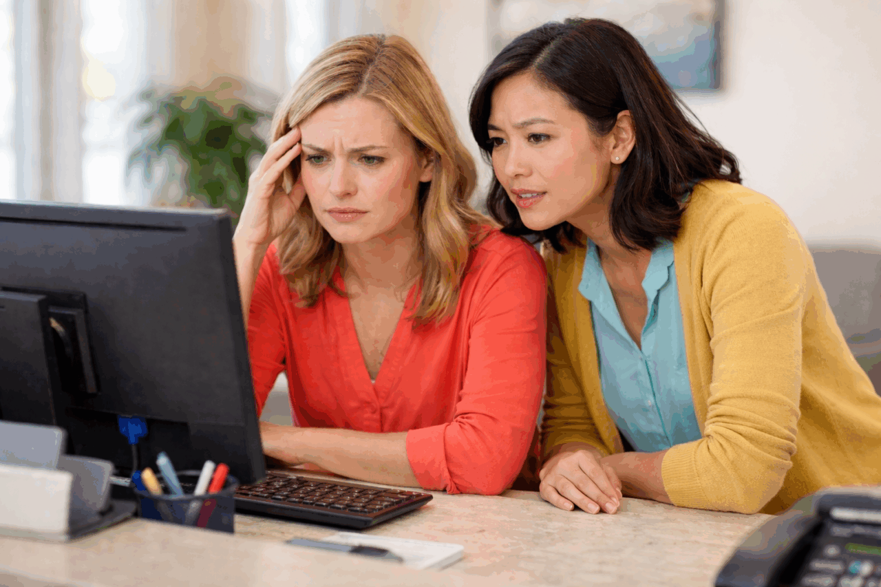 Two women in a dental office appear frustrated as they review information across disconnected systems on a computer.