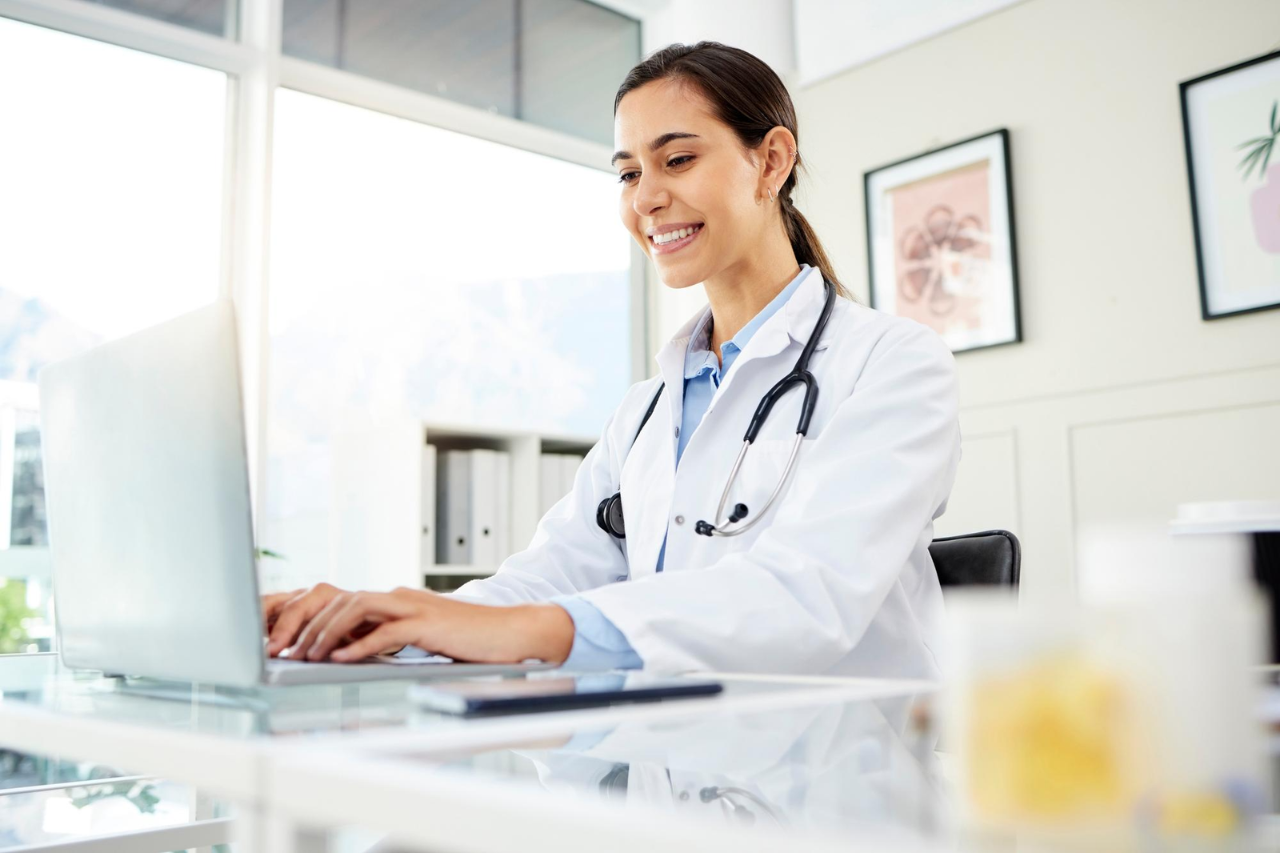 Female doctor using a laptop with a stethoscope in a bright medical office