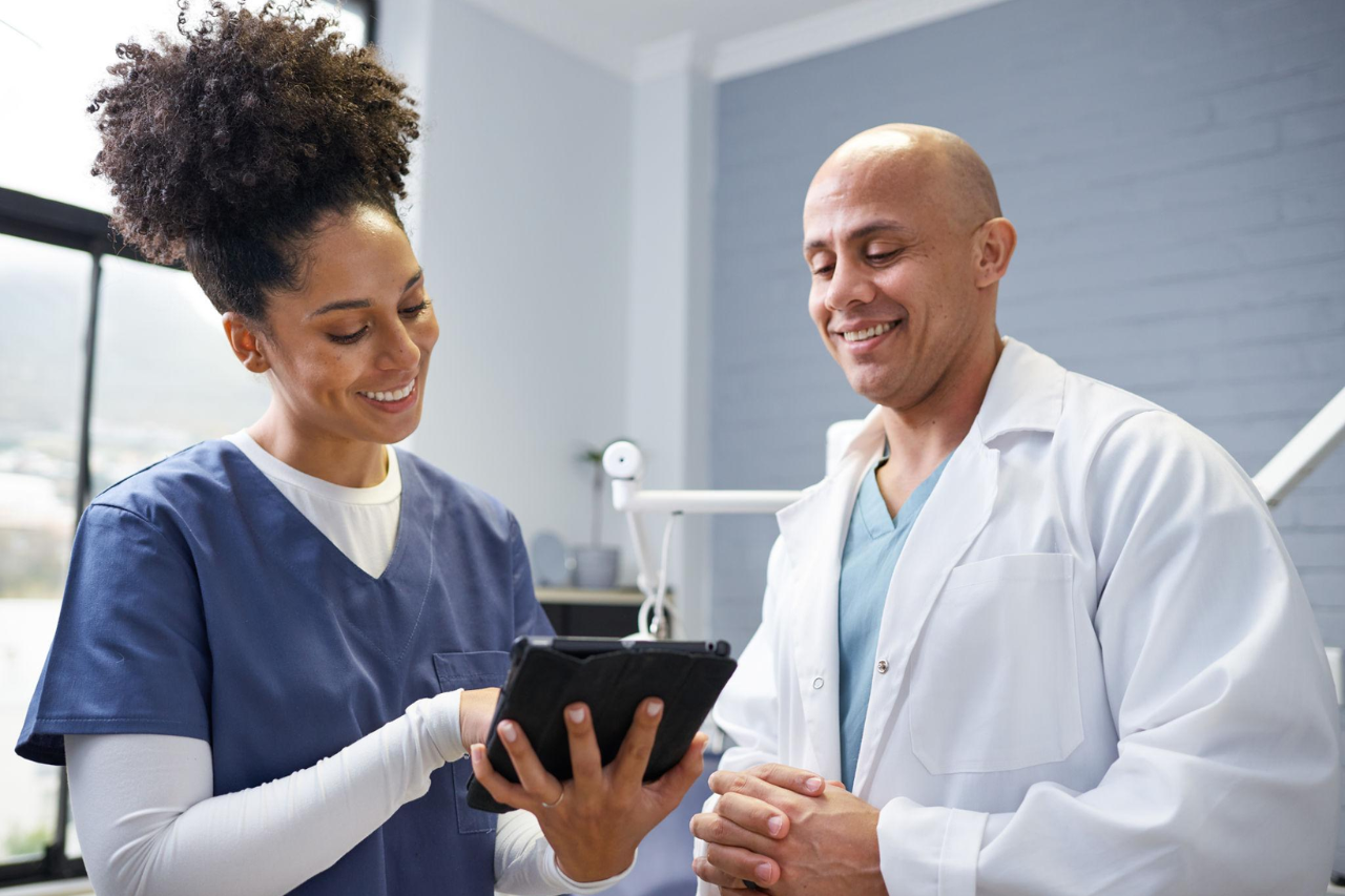 Doctor and nurse collaborating while reviewing patient information on a tablet in a clinic