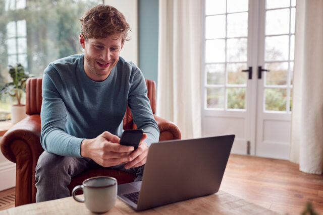 Man uses his phone at home to reconnect with his healthcare practice through Solutionreach patient recall messaging.